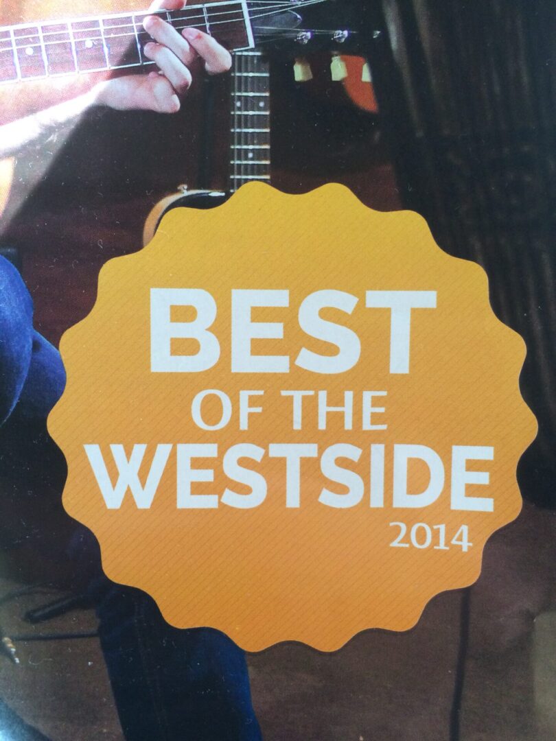 A person holding a guitar with the words best of the westside 2 0 1 4 on it.