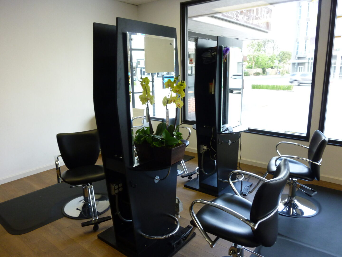 A salon with black chairs and mirrors in it