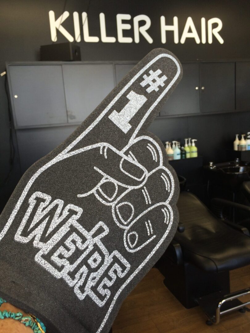A foam hand with the number 1 and the word " we 're here ".