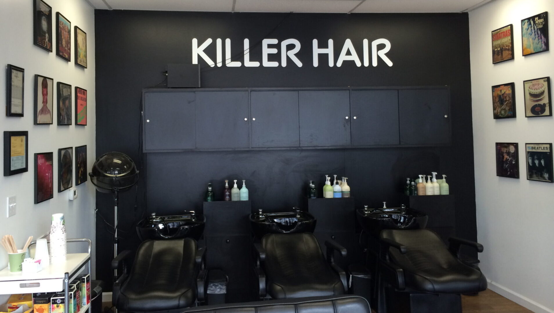 A room with black chairs and a sign that reads " killer hair ".