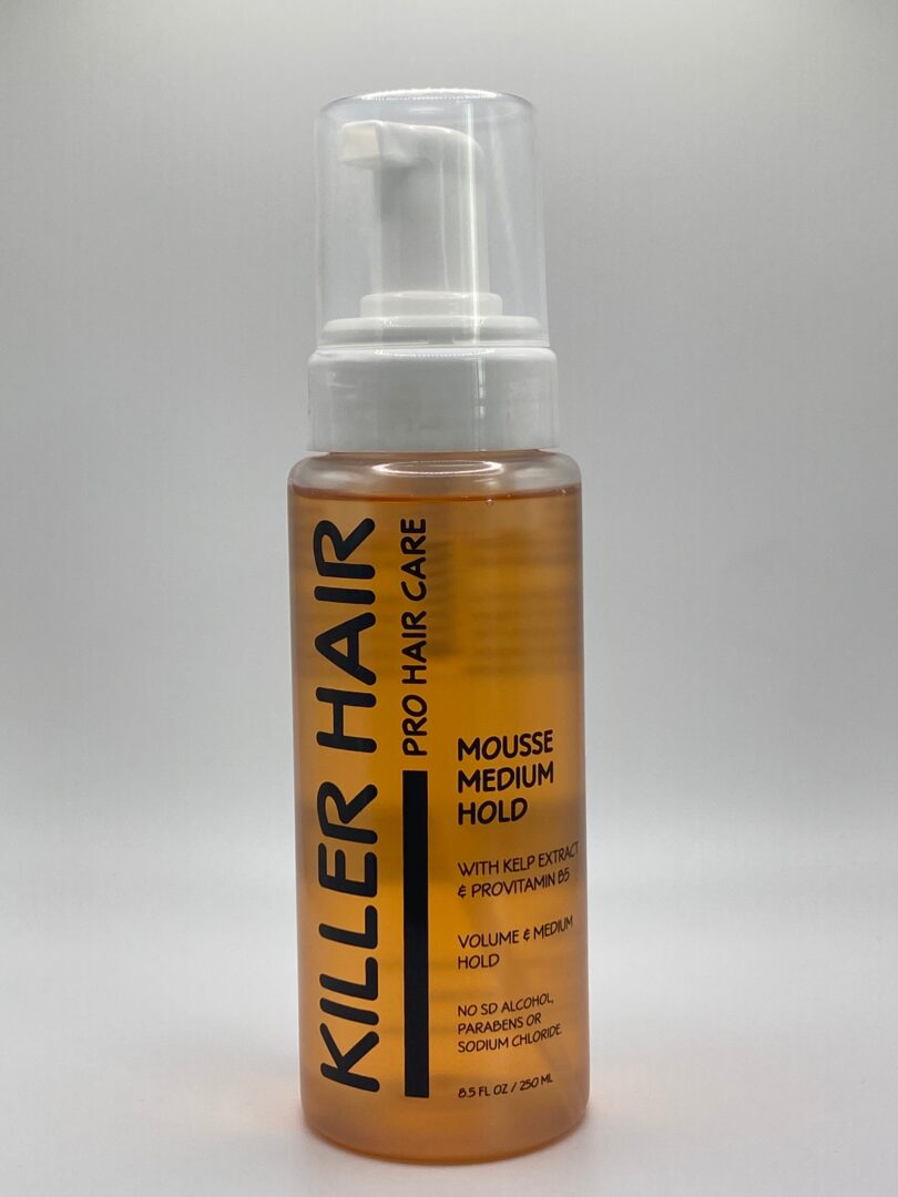 A bottle of hair mousse is shown on top of a white surface.