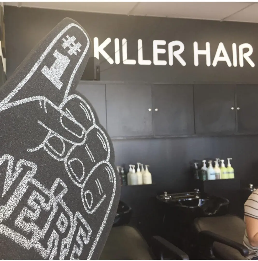 A black wall with the words " killer hair " written on it.